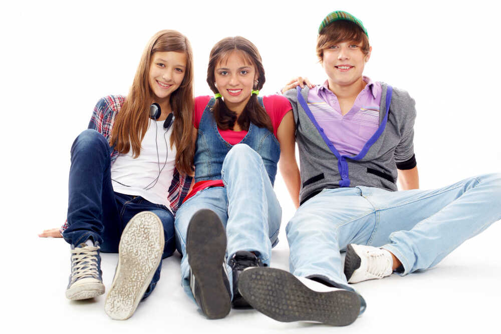 trzech nastolatków siedzi na podłodze i uśmiecha się