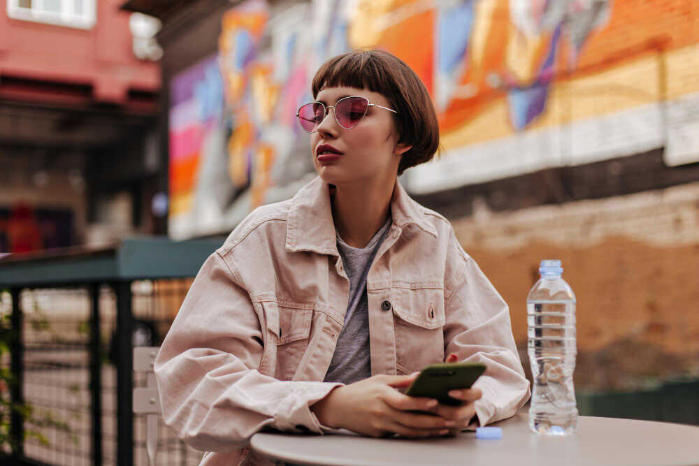 stylowa nastolatka z okularami iphone w ręku
